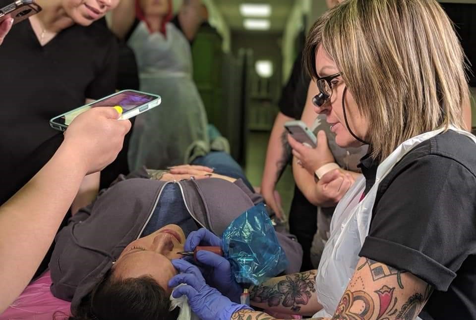 Teryn Darling tattooing an eyeliner with students watching