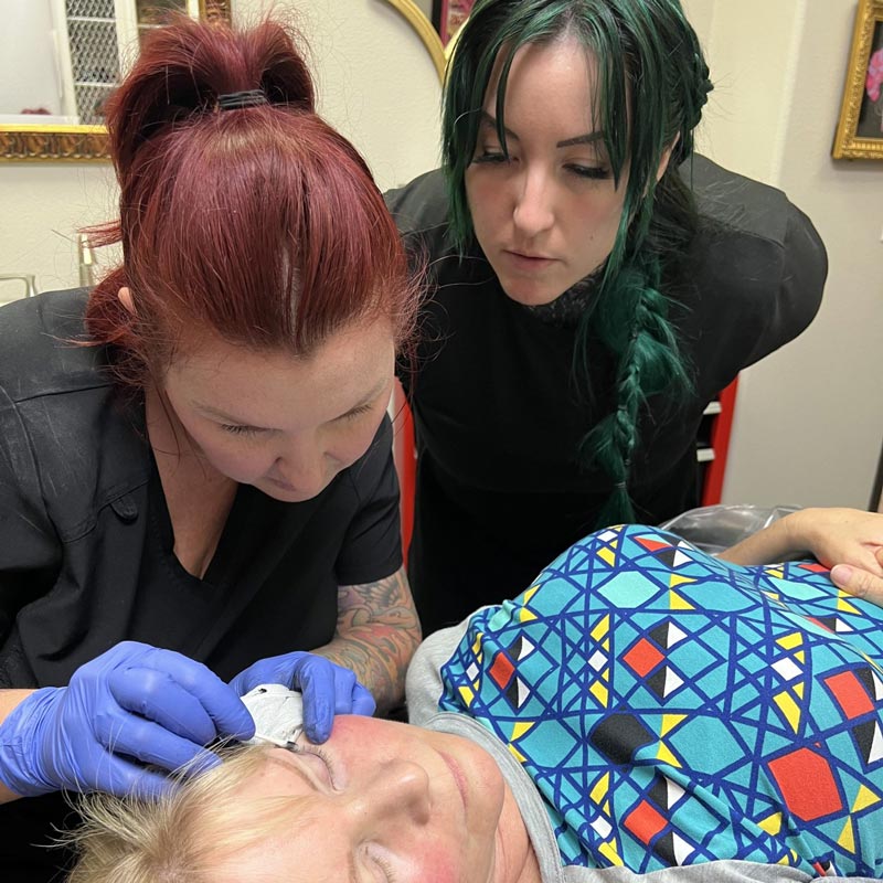 Artist Michon watching Artist Amy perform eyeliner procedure