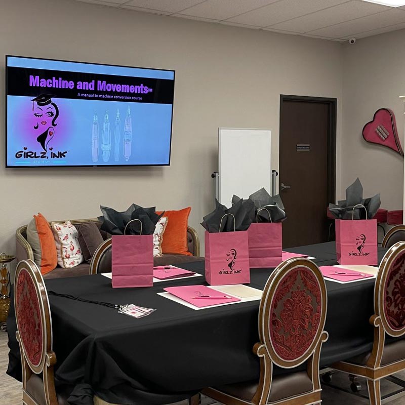 The training area of Girlz Ink with a powerpoint on the tv and 4 gift-bags on the table.